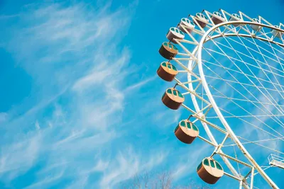 Looking up at a Ferris wheel with a blue sky and wispy clouds